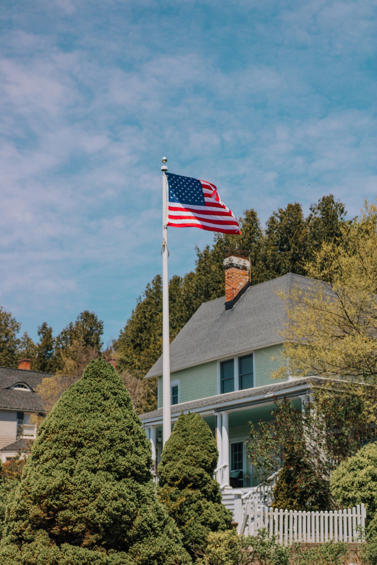 American flag flying above a well-kept home with a premium roof